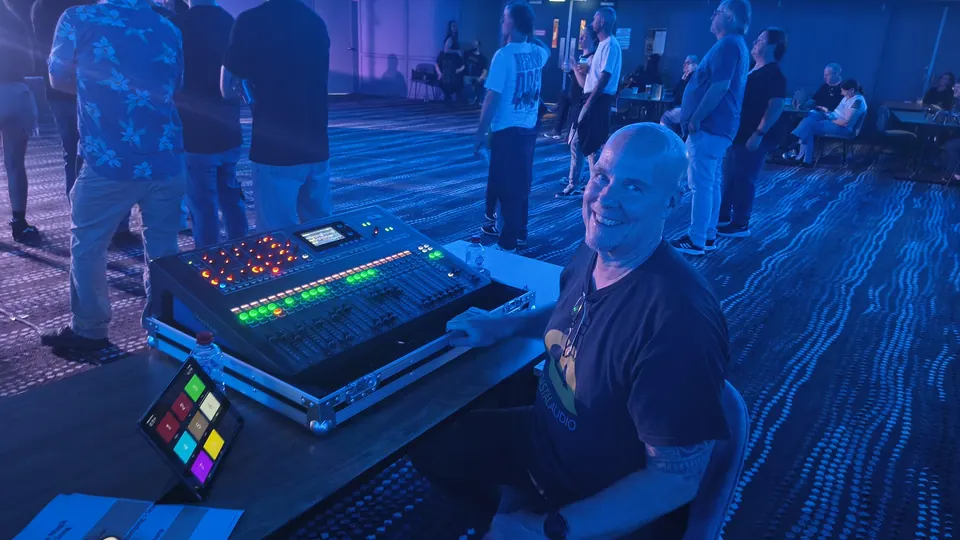 Andy Taylor smiling at the mixing desk during a show