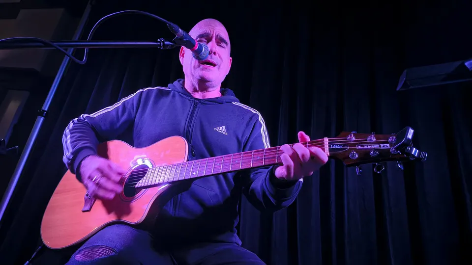 A singer playing acoustic guitar on stage