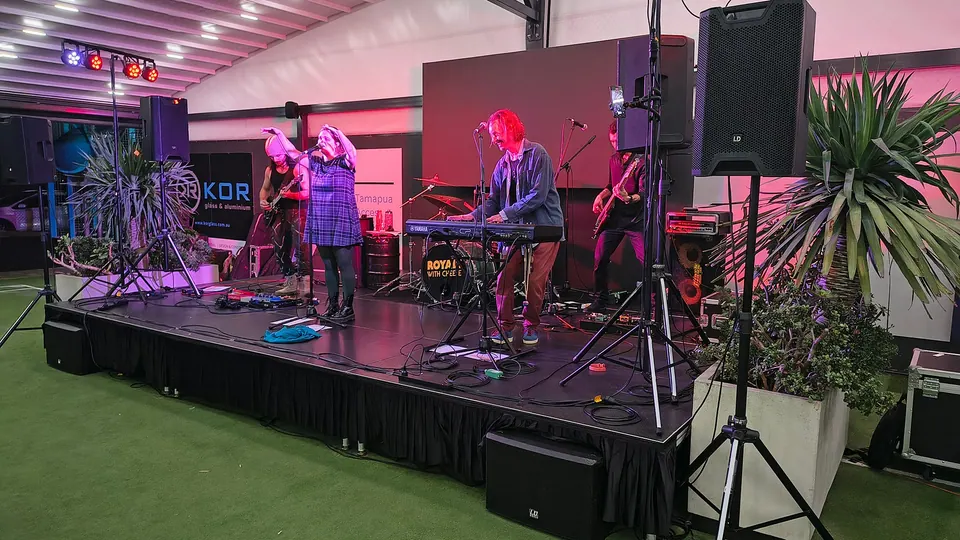 A band playing on a covered outdoor stage with speakers on stands