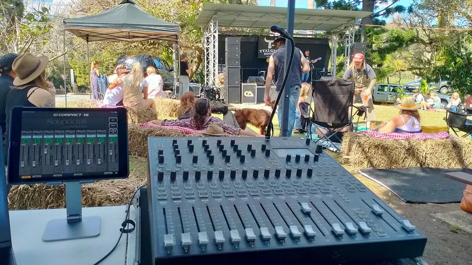 An outdoor show seen from the mixing desk, with hay bales in front of the stage
