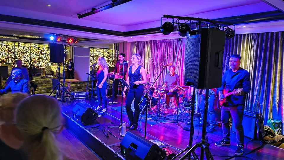 A band with two singers on stage under purple and gold light