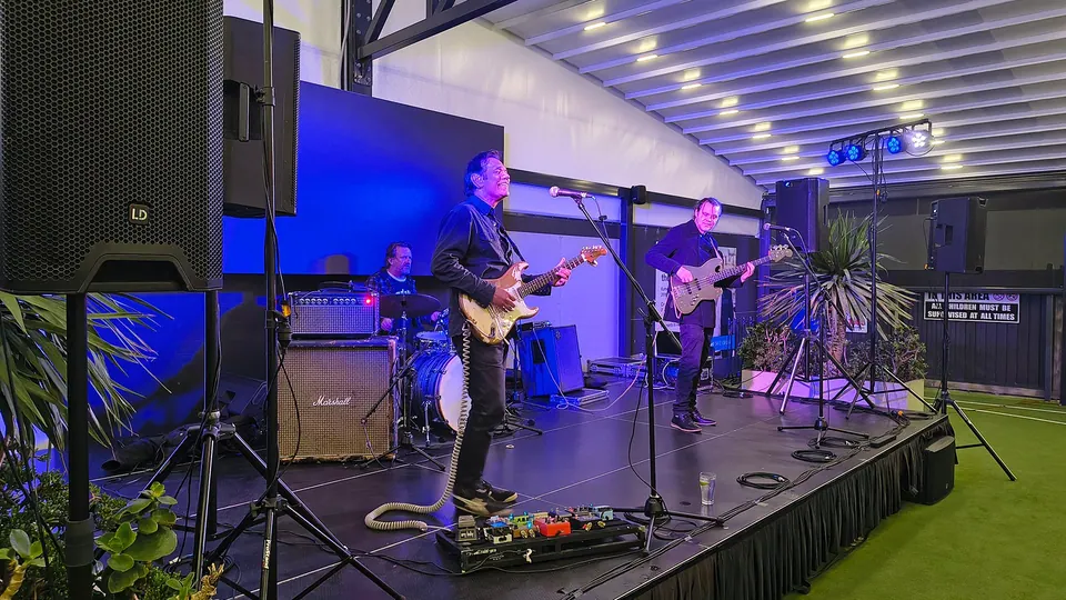 A guitarist and a bass player on an outdoor stage at dusk